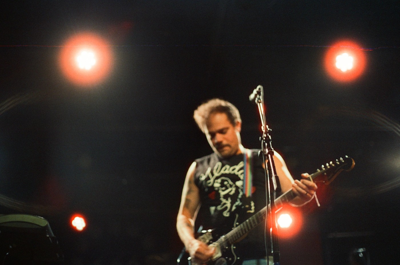 a man is playing a guitar on a stage in front of a microphone .