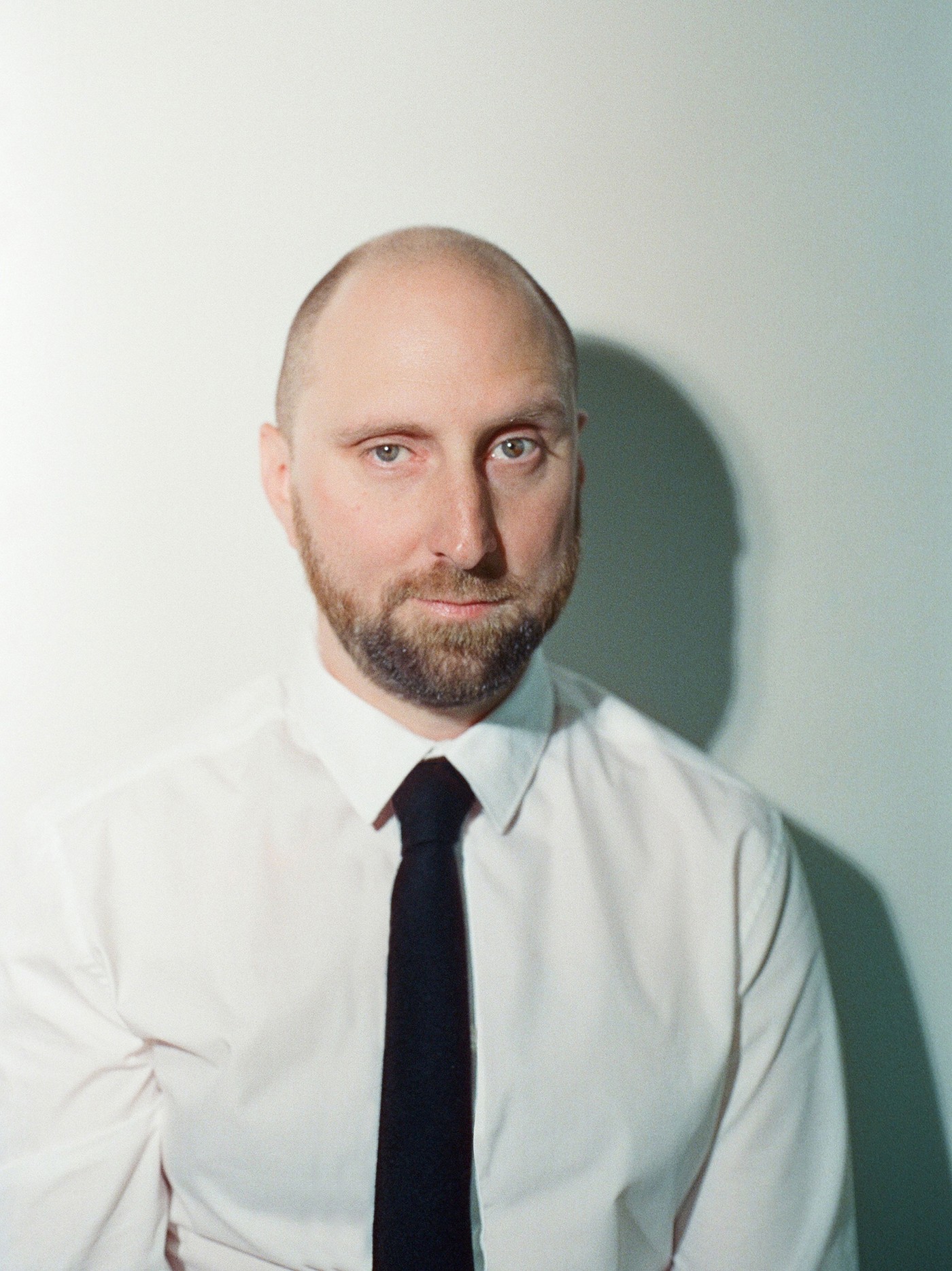 Chris Donahue, a man with a beard wearing a white shirt and black tie