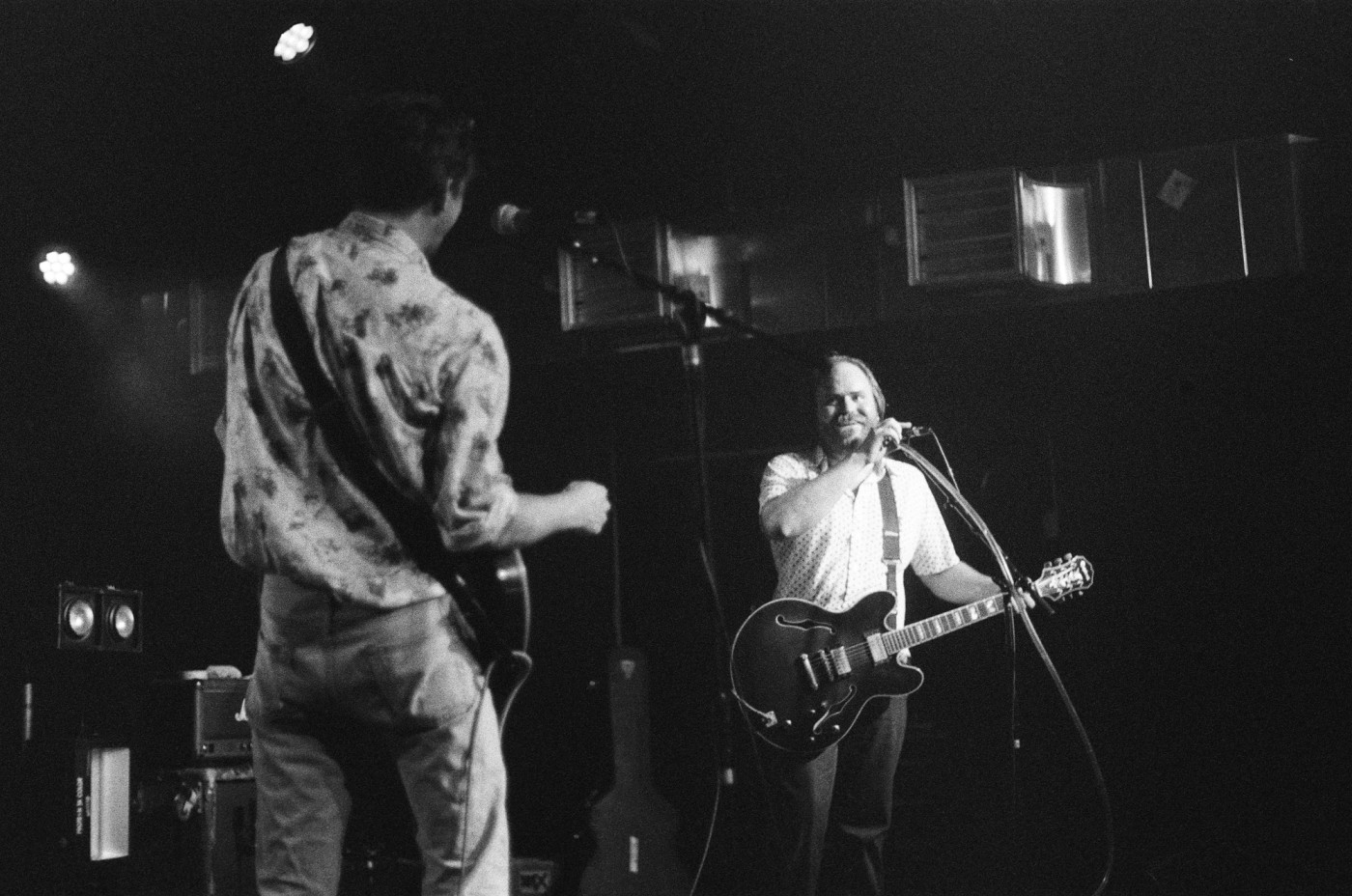 two men are playing guitars and singing into microphones on a stage .