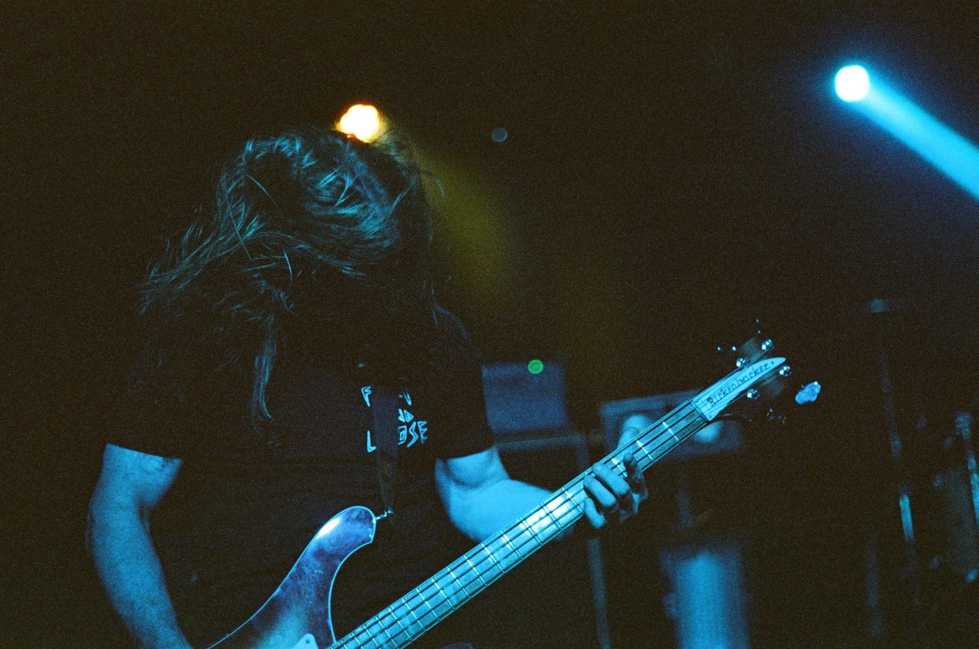 a man is playing a bass guitar on a stage in a dark room .