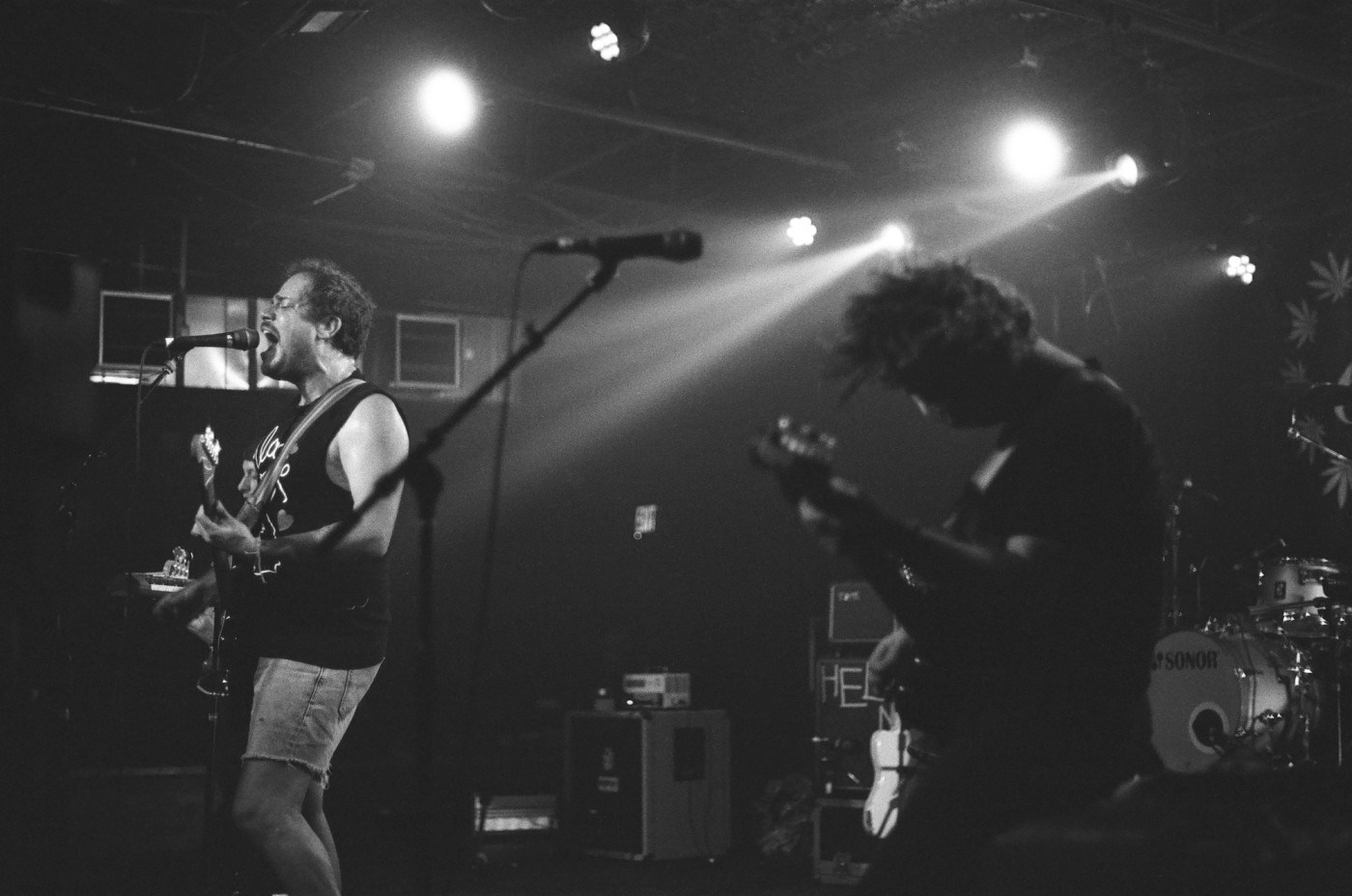 a man is singing into a microphone while another man plays a guitar on stage .