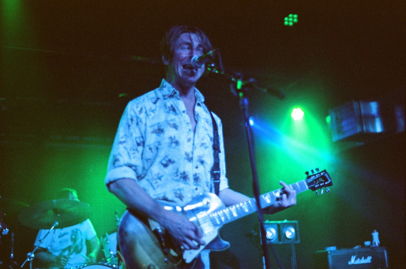 a man is playing a guitar and singing into a microphone on a stage .