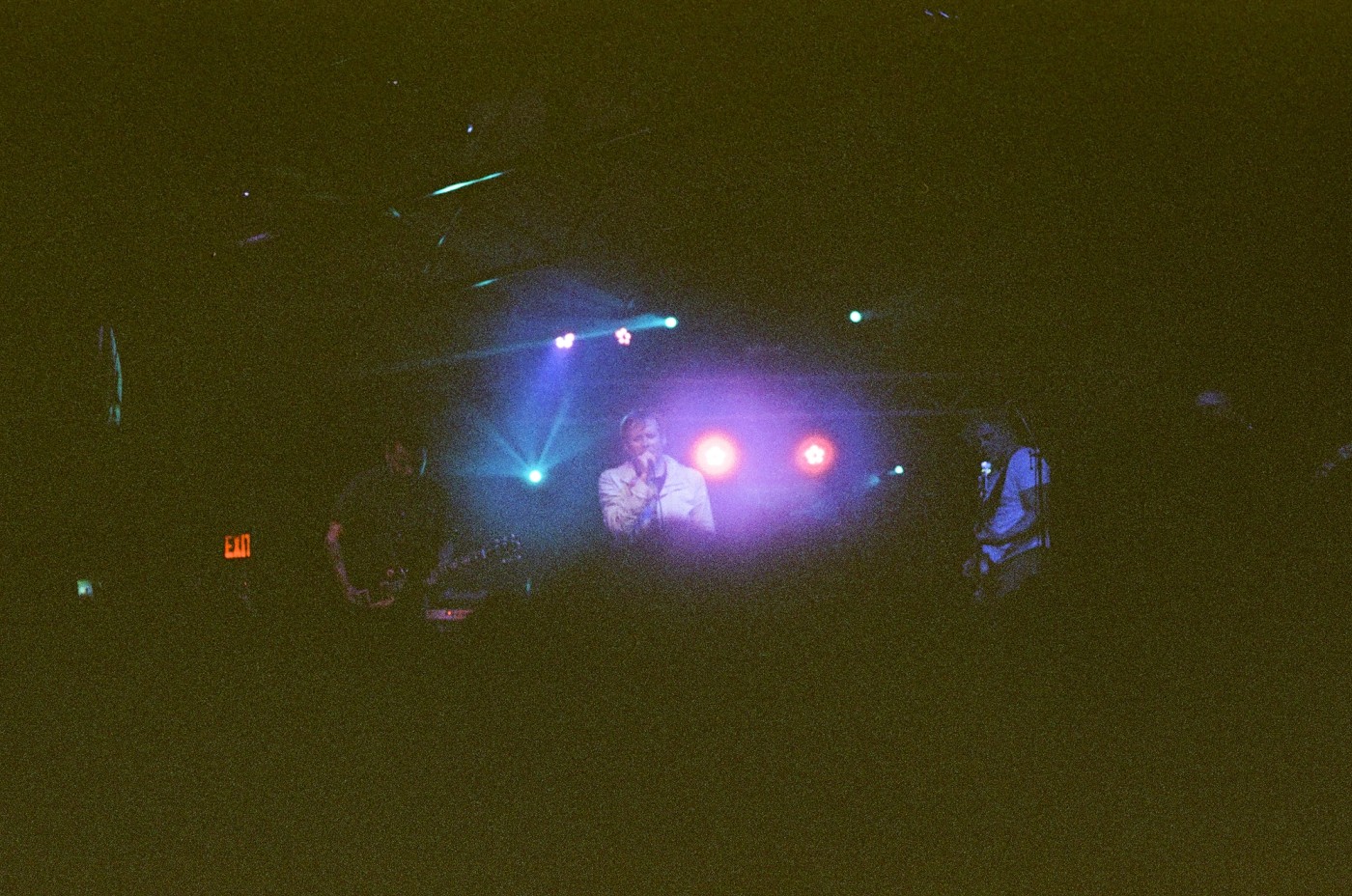 a man is singing into a microphone on a stage in a dark room .