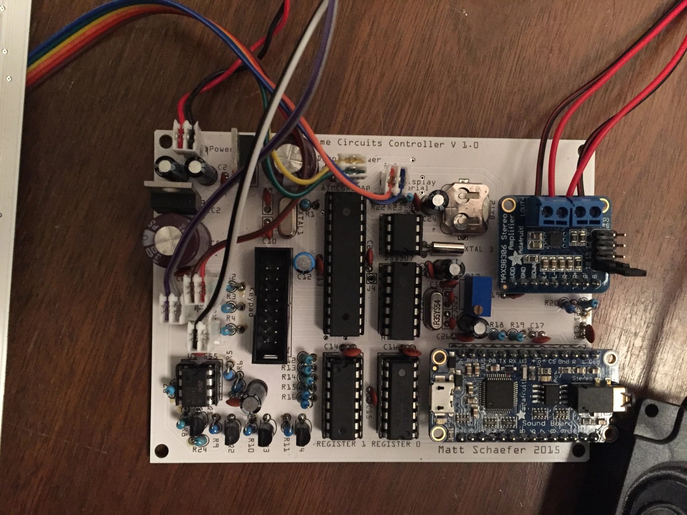 a circuit board with a lot of wires connected to it is sitting on a wooden table .
