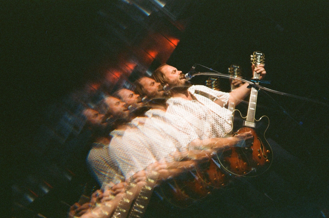 a man is playing a guitar and singing into a microphone on a stage .