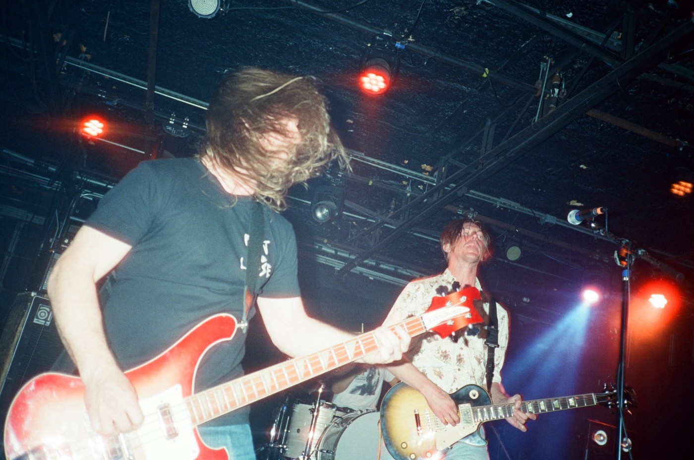 two men are playing guitars on a stage in a dark room .