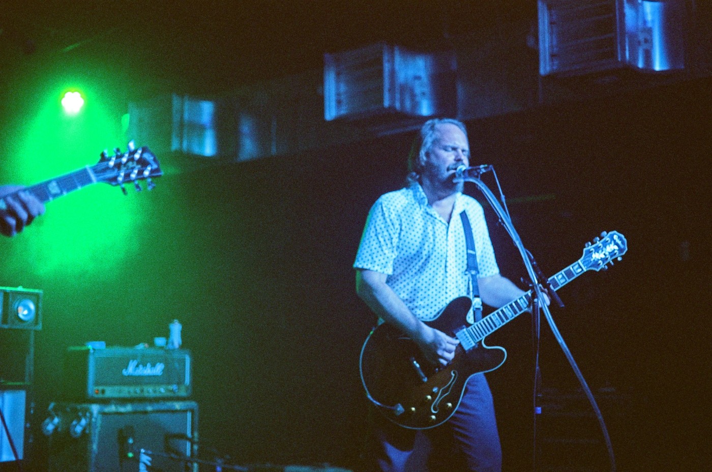 a man is playing a guitar and singing into a microphone on a stage .