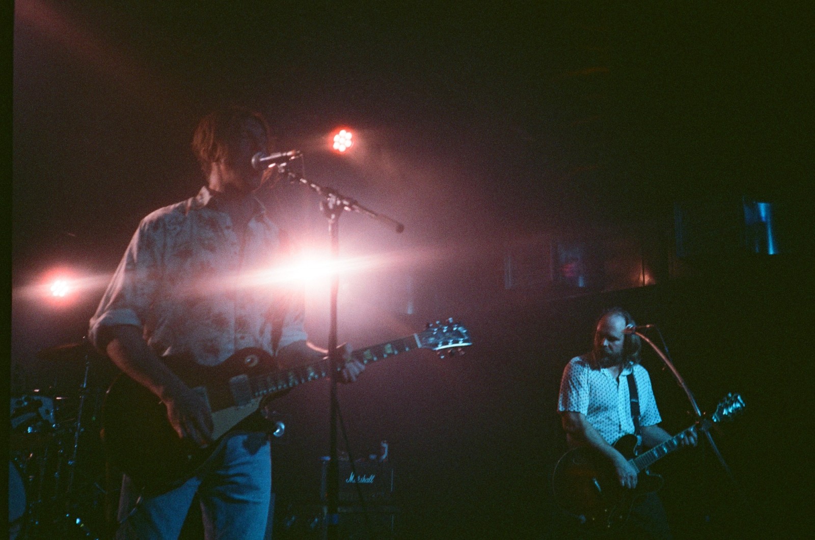 two men are playing guitars and singing into microphones on a stage .