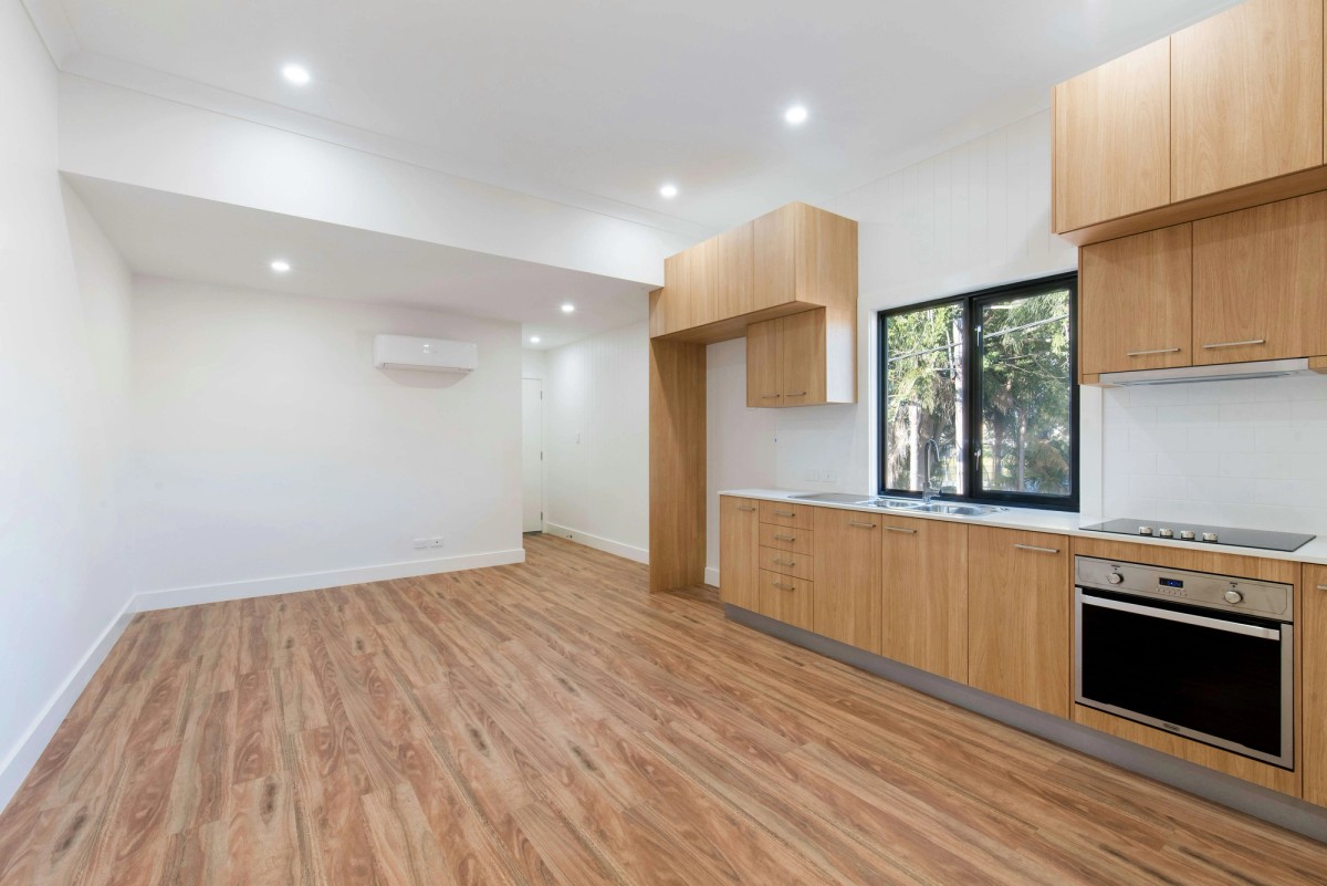 an empty kitchen with wooden cabinets , stainless steel appliances , and a large window .