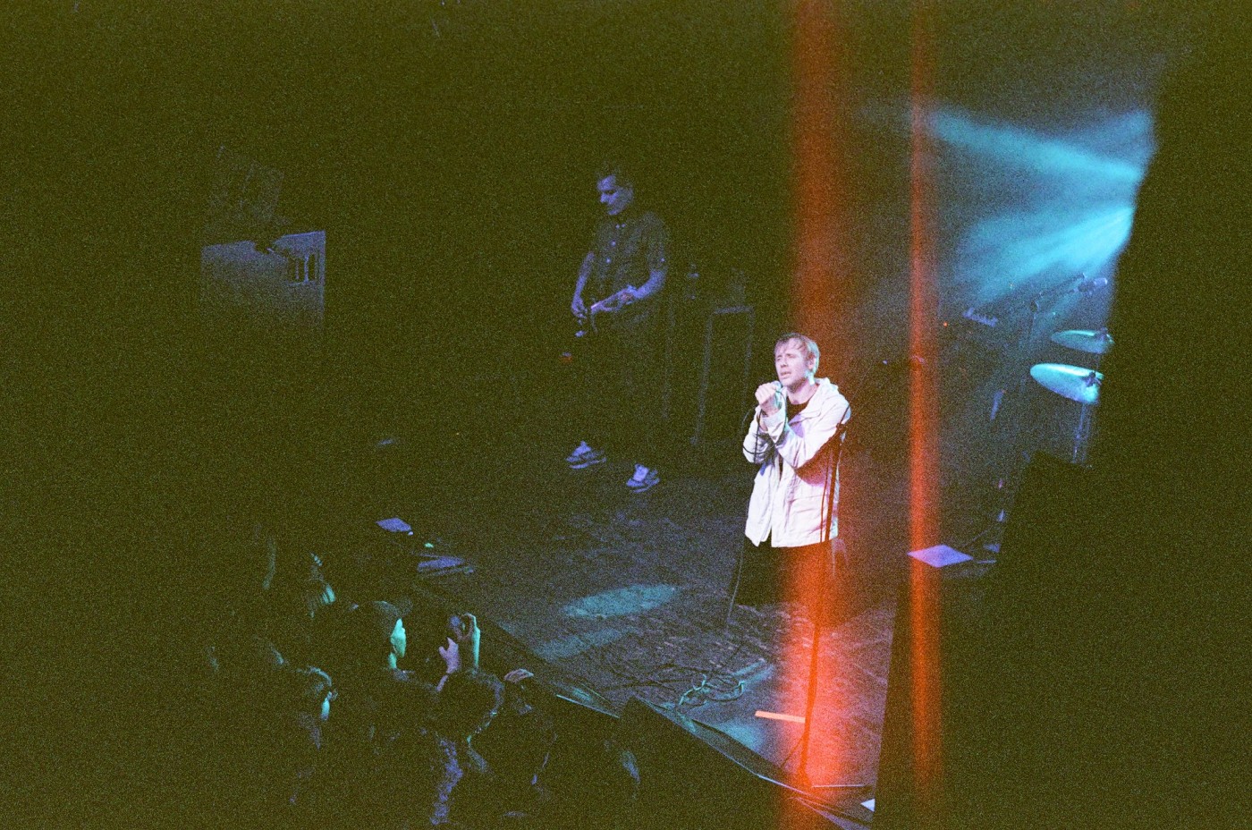 a man is singing into a microphone on a stage in front of a crowd .