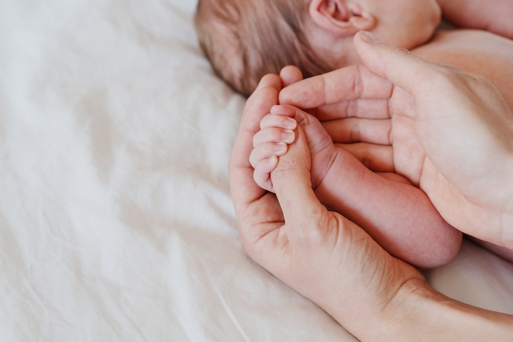 Image Parent holding a newborn’s hand on a hospital bed, representing birth injury concerns and delayed treatment during labor in Philadelphia.