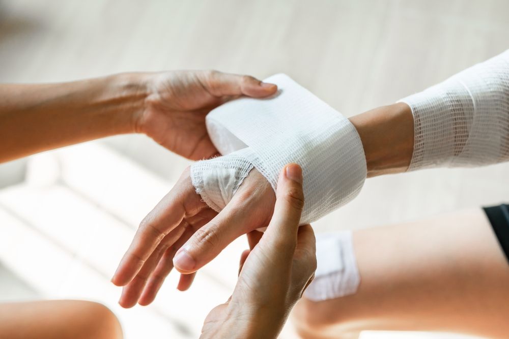 Person wrapping a bandage around an injured hand, representing severe burn injury treatment and recovery in Philadelphia.