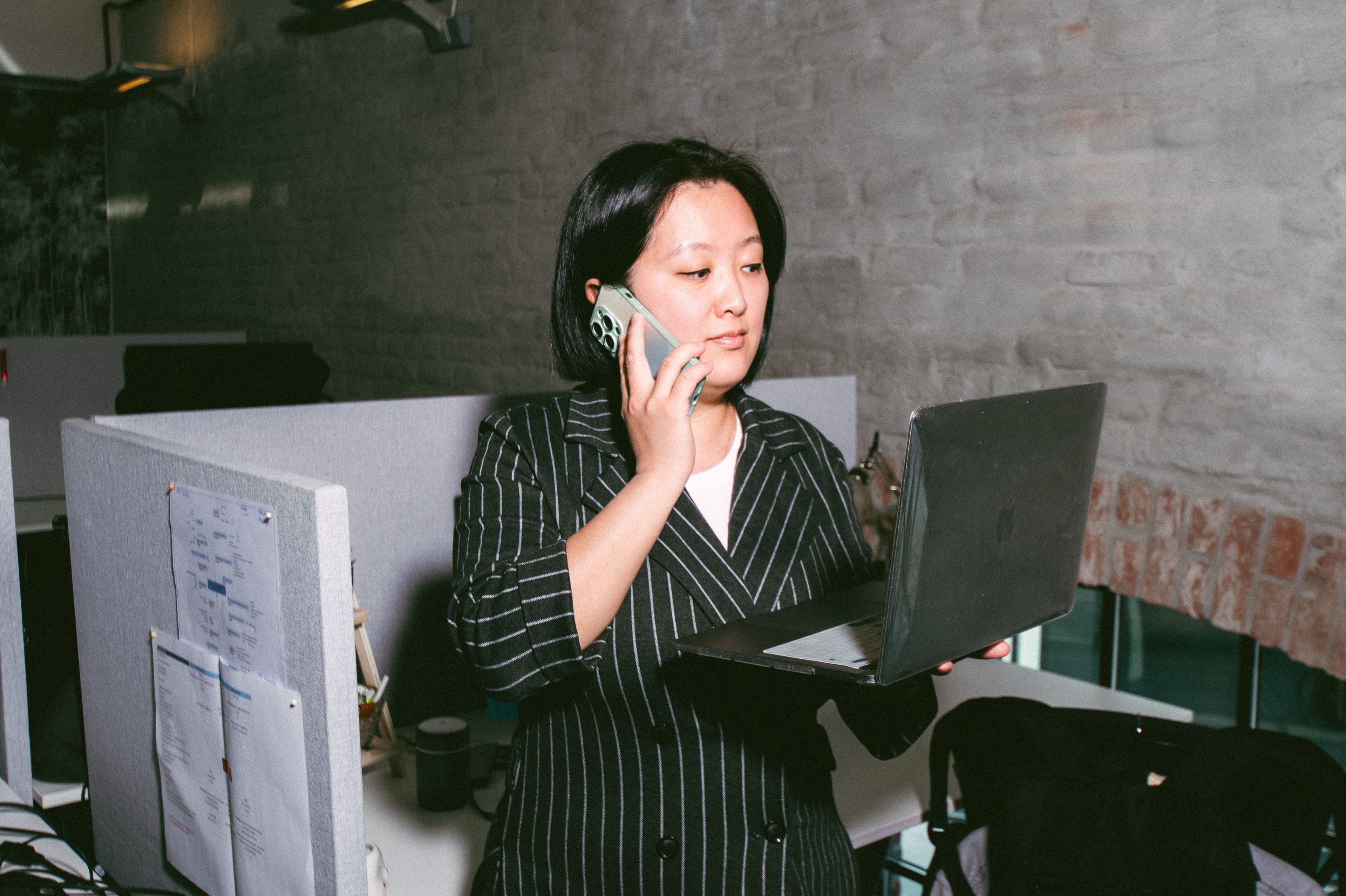A woman holding her computer while takling in the phone.