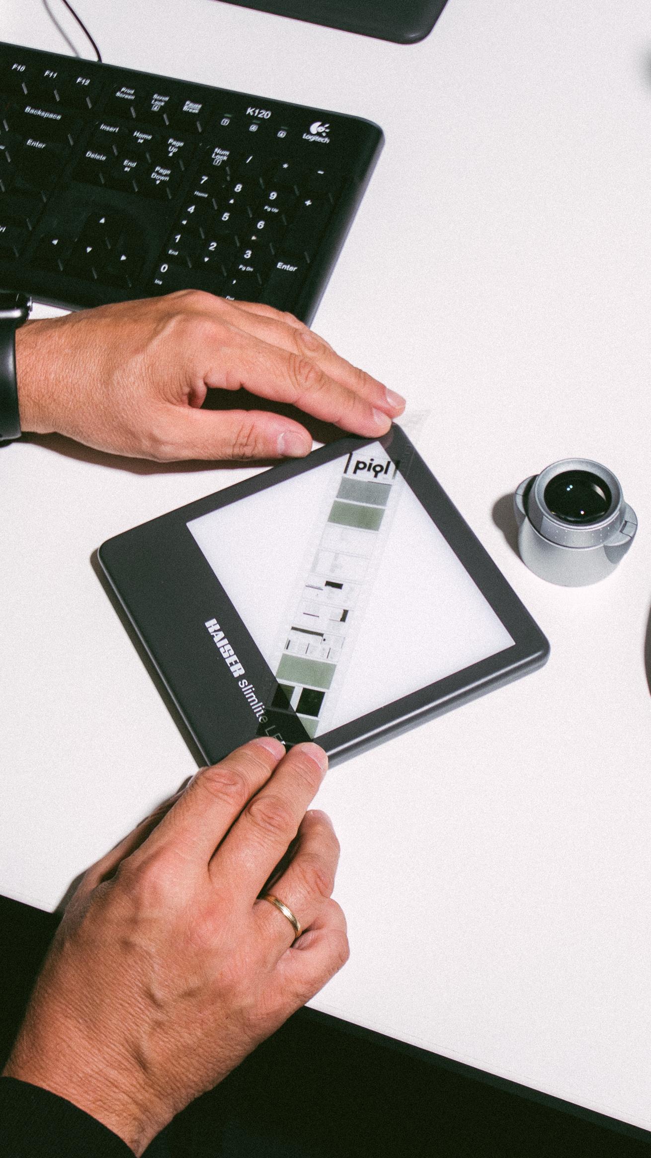 A man holding a 35mm film strip above a light tablet.