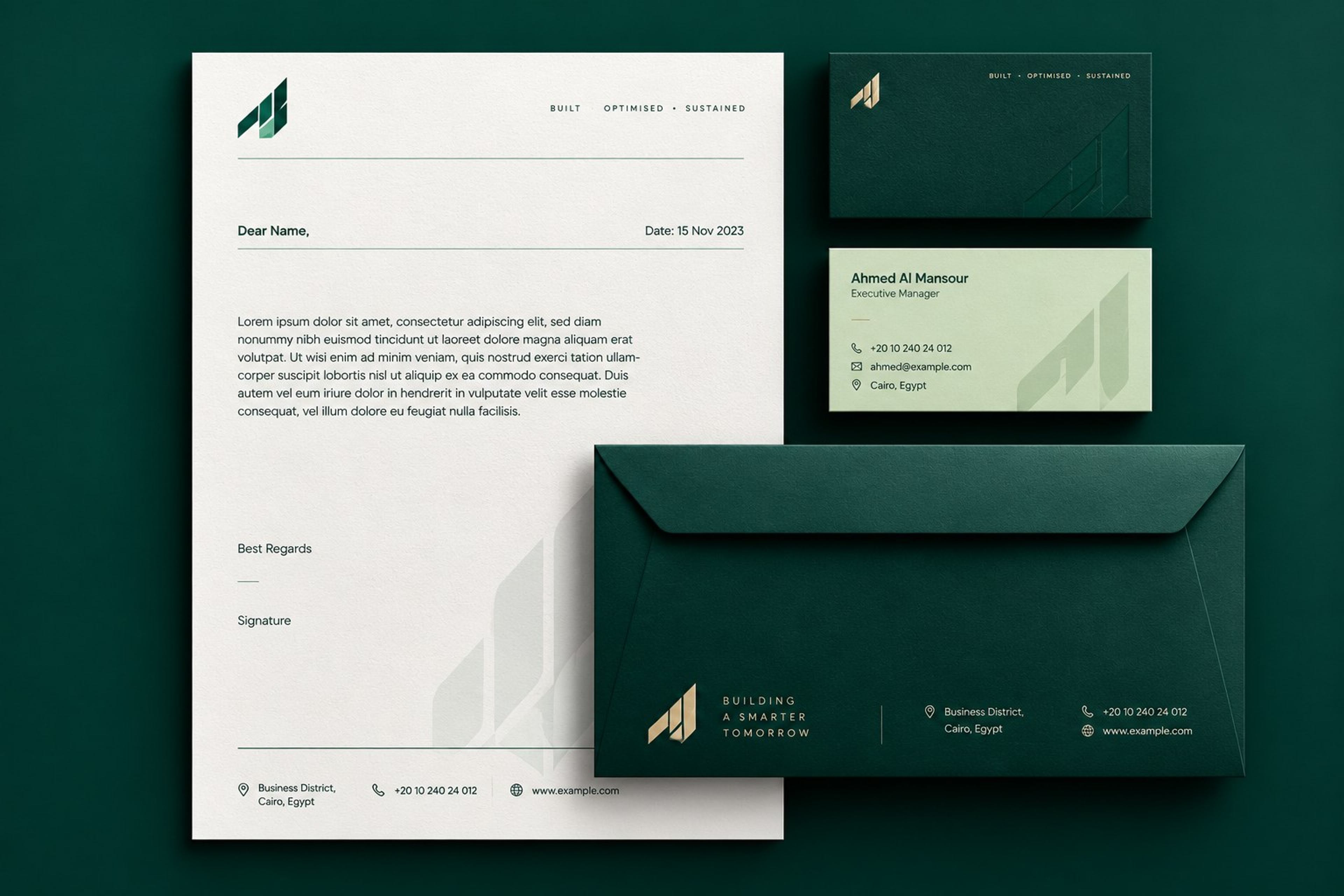 A property developer stationery set on deep green: letterhead, two business cards and an envelope, each carrying a folded monogram in green and gold.