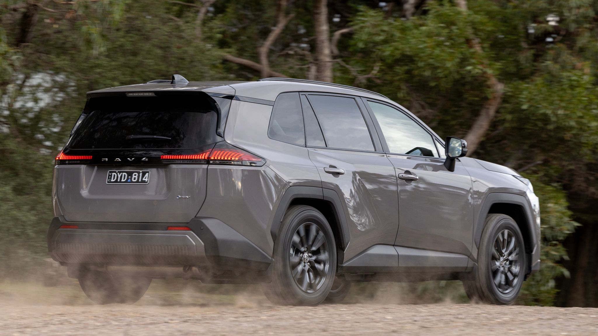 Grey new generation Toyota RAV4 driving on a tree lined road