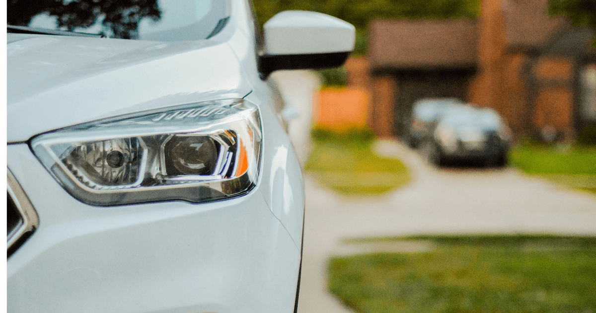 Close up of a white car headlight with a residential street blurred in the background