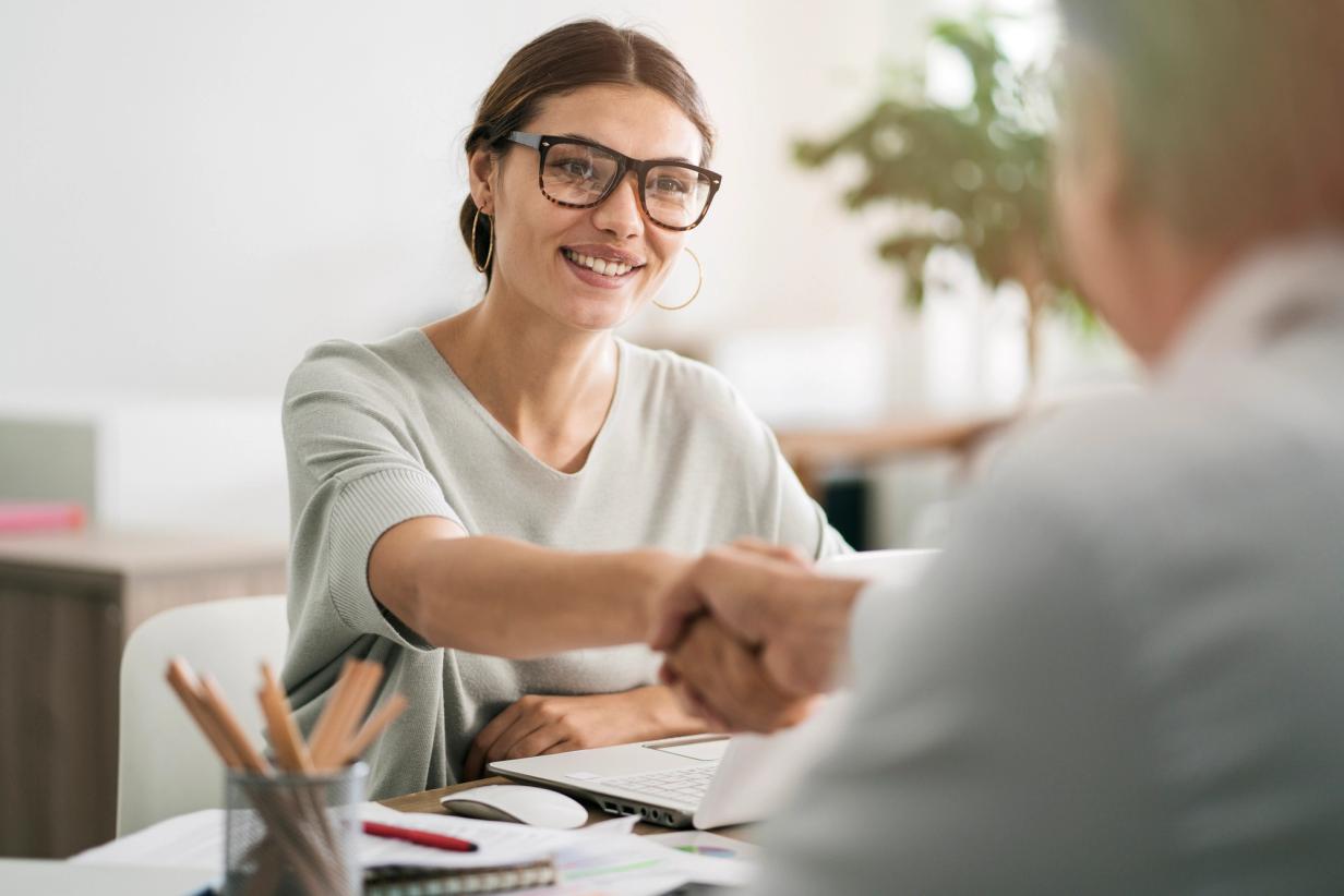 Car buyer reviewing negotiation strategies across from a dealership consultant at a vehicle showroom.