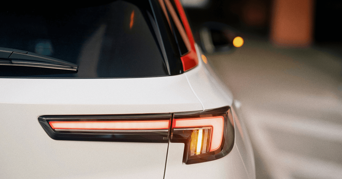 Close up of a white car rear taillight illuminated in a dim setting.