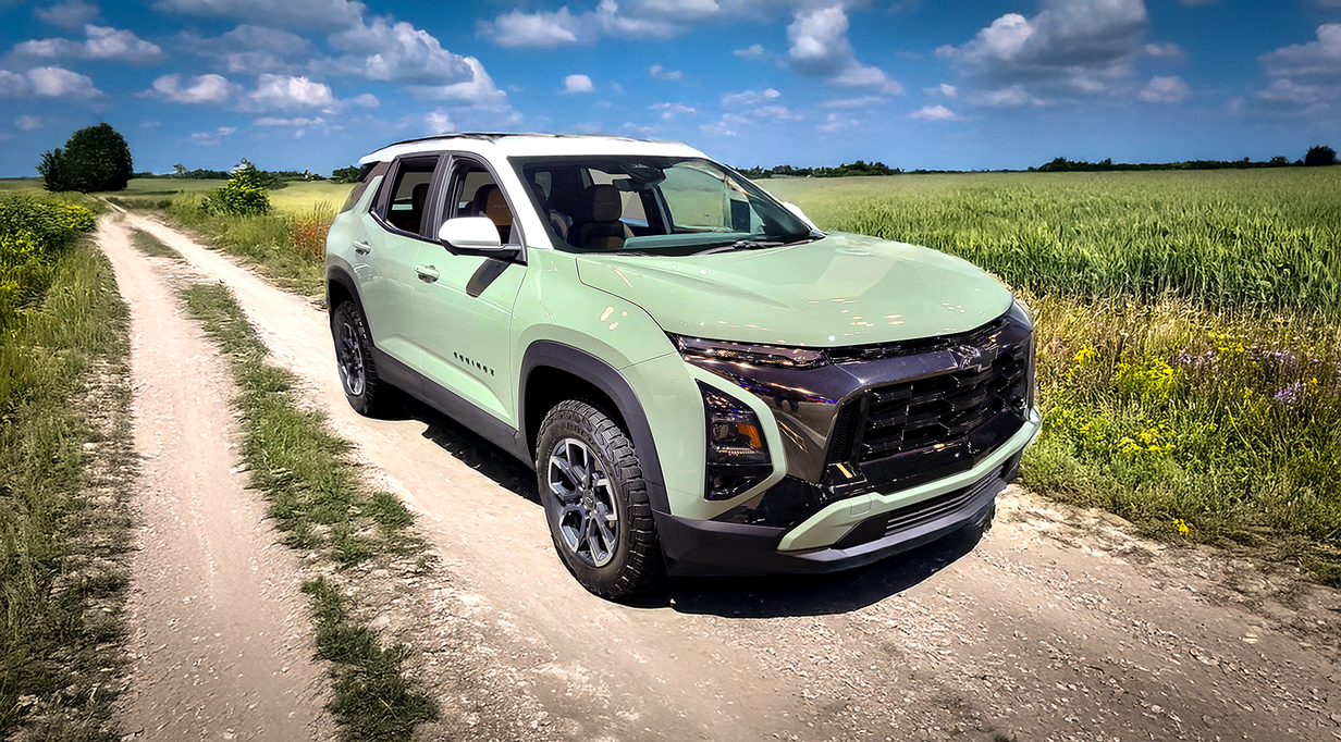 Light green 2025 Chevrolet Equinox parked on a dirt road beside a field on a sunny day.