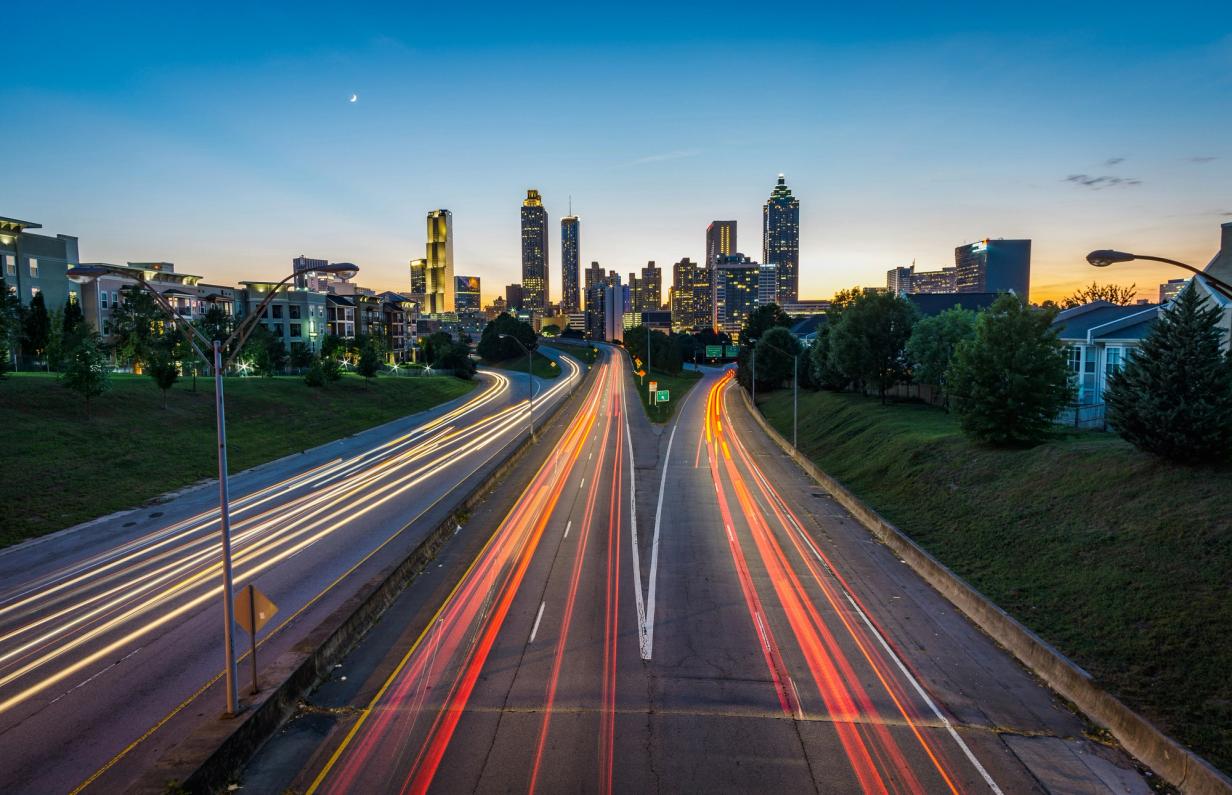 Cars driving on a highway at night with lights stretched into long trails.
