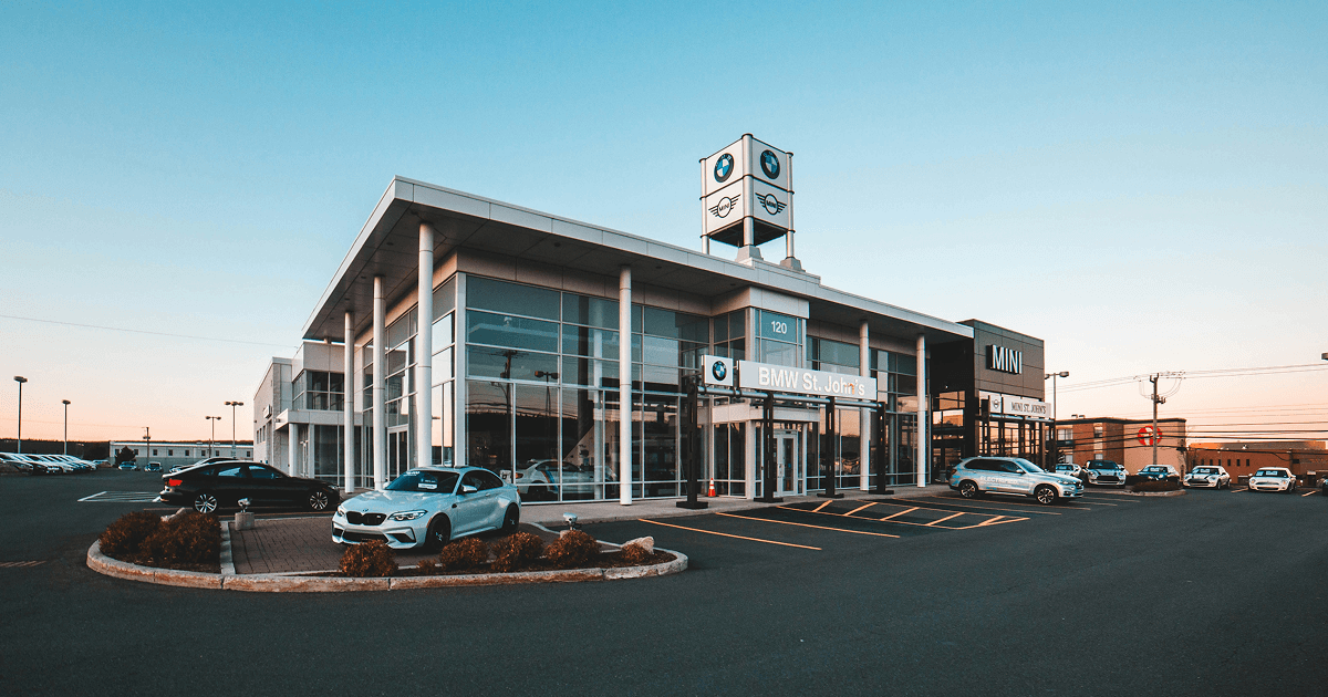 Exterior of a modern car dealership with several vehicles parked outside at dusk