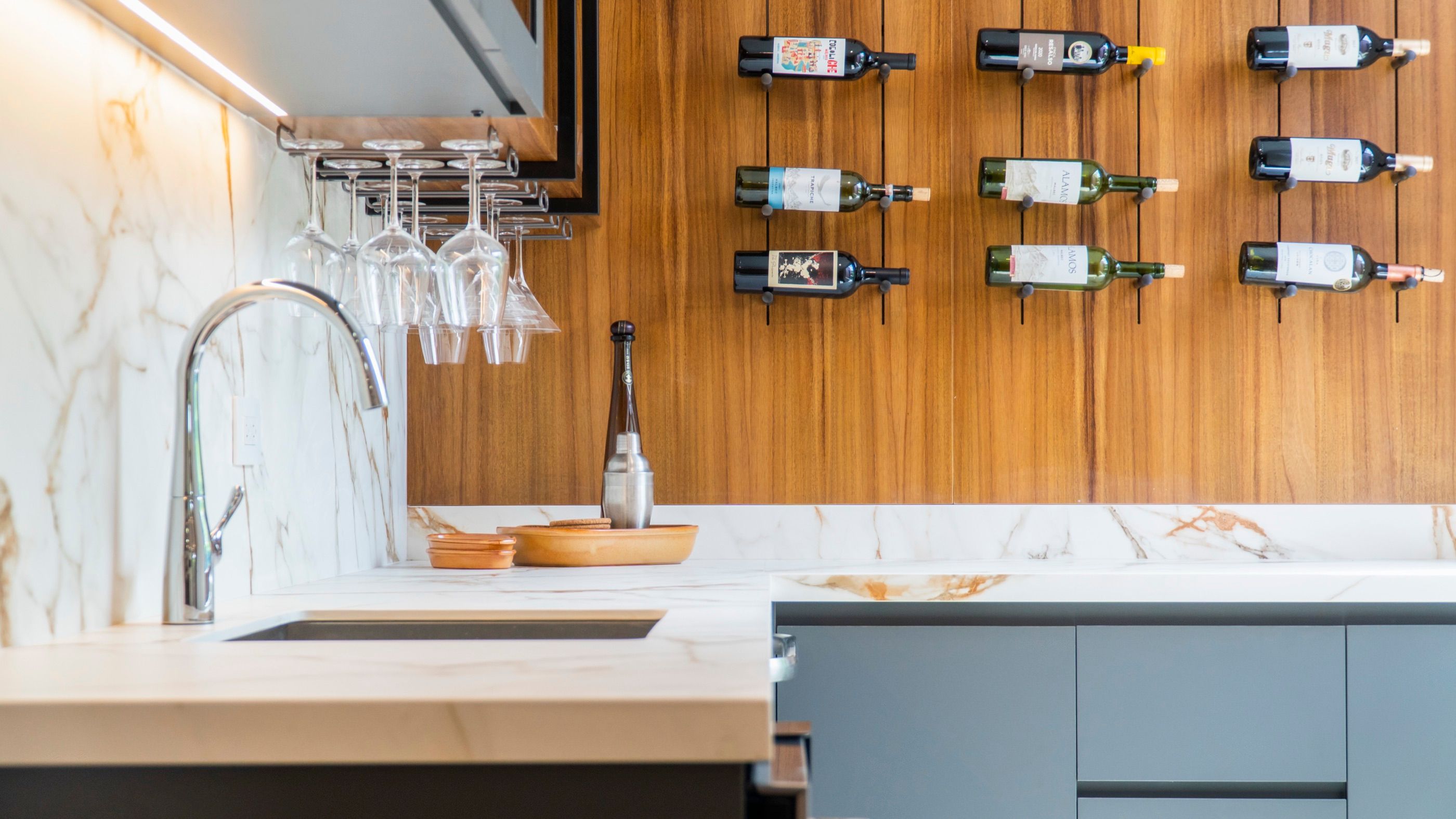 Kitchen island in marble and wood with a wall-mounted wine rack