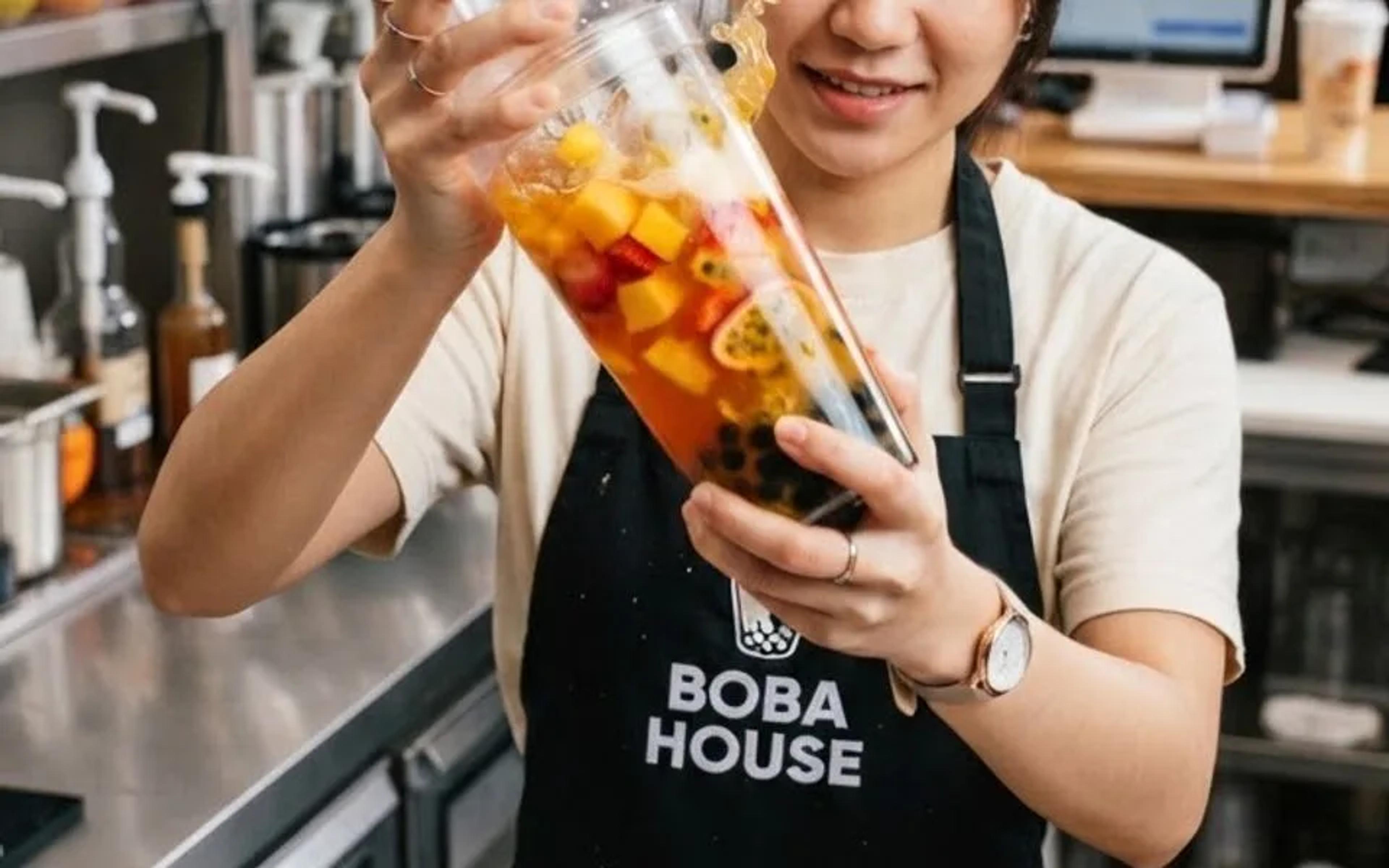 A Boba House team member sealing a freshly made fruit tea at the counter