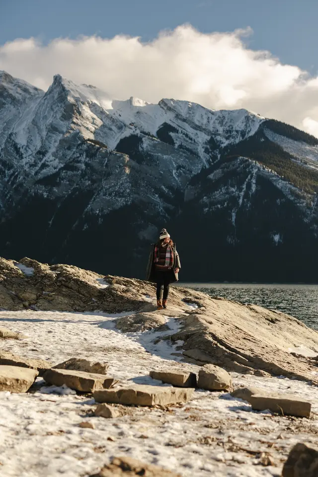 Julia Francis walking on the rocky shore of a large lake in the middle of the Rocky Mountains of Banff National Park in Alberta, Canada