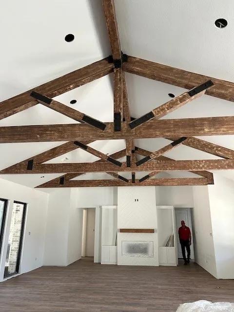 New vaulted ceiling with exposed wood beams and trusses in a living room under construction
