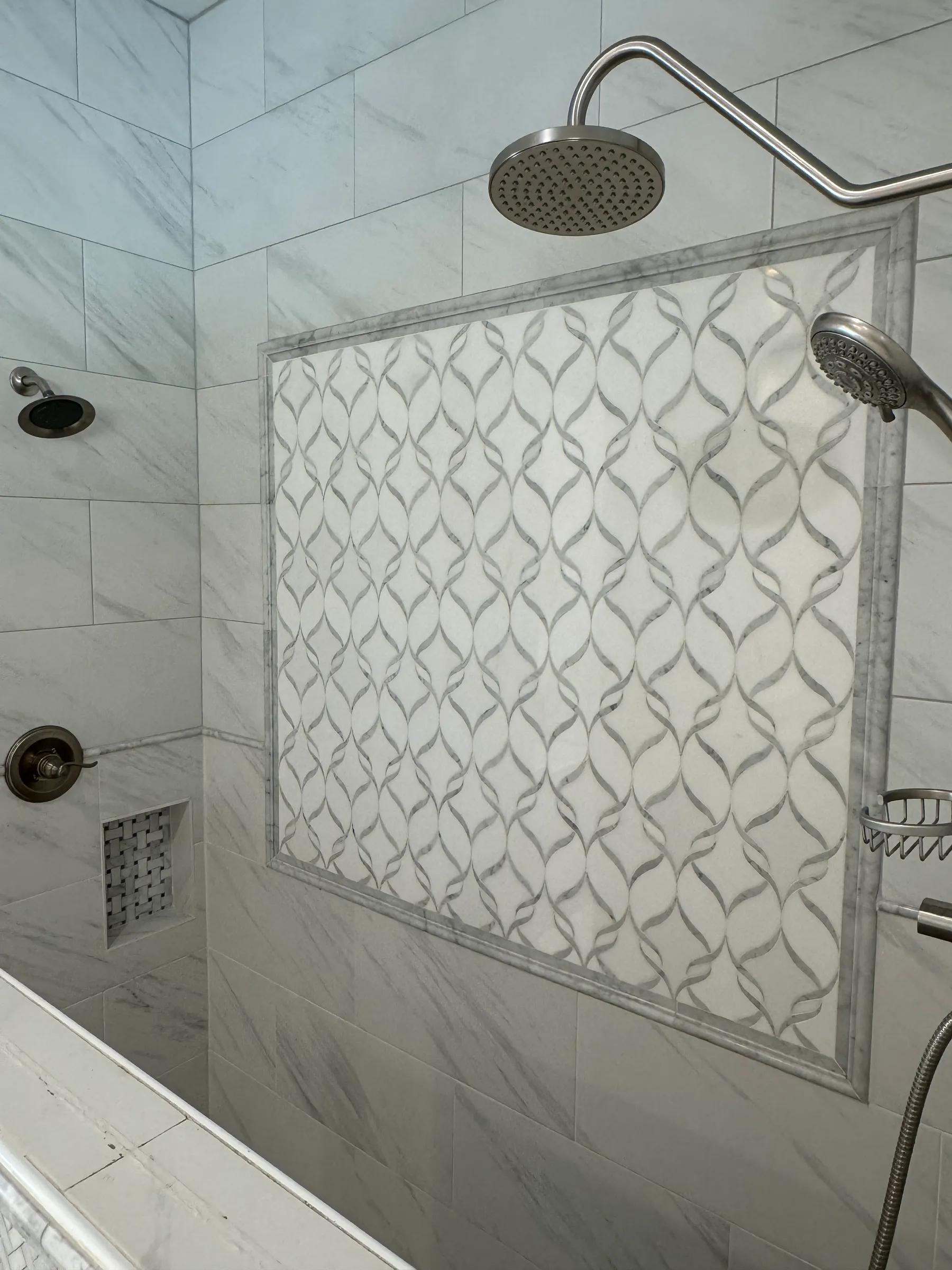 Walk-in shower with a rain head, handheld sprayer, and a framed marble mosaic accent wall
