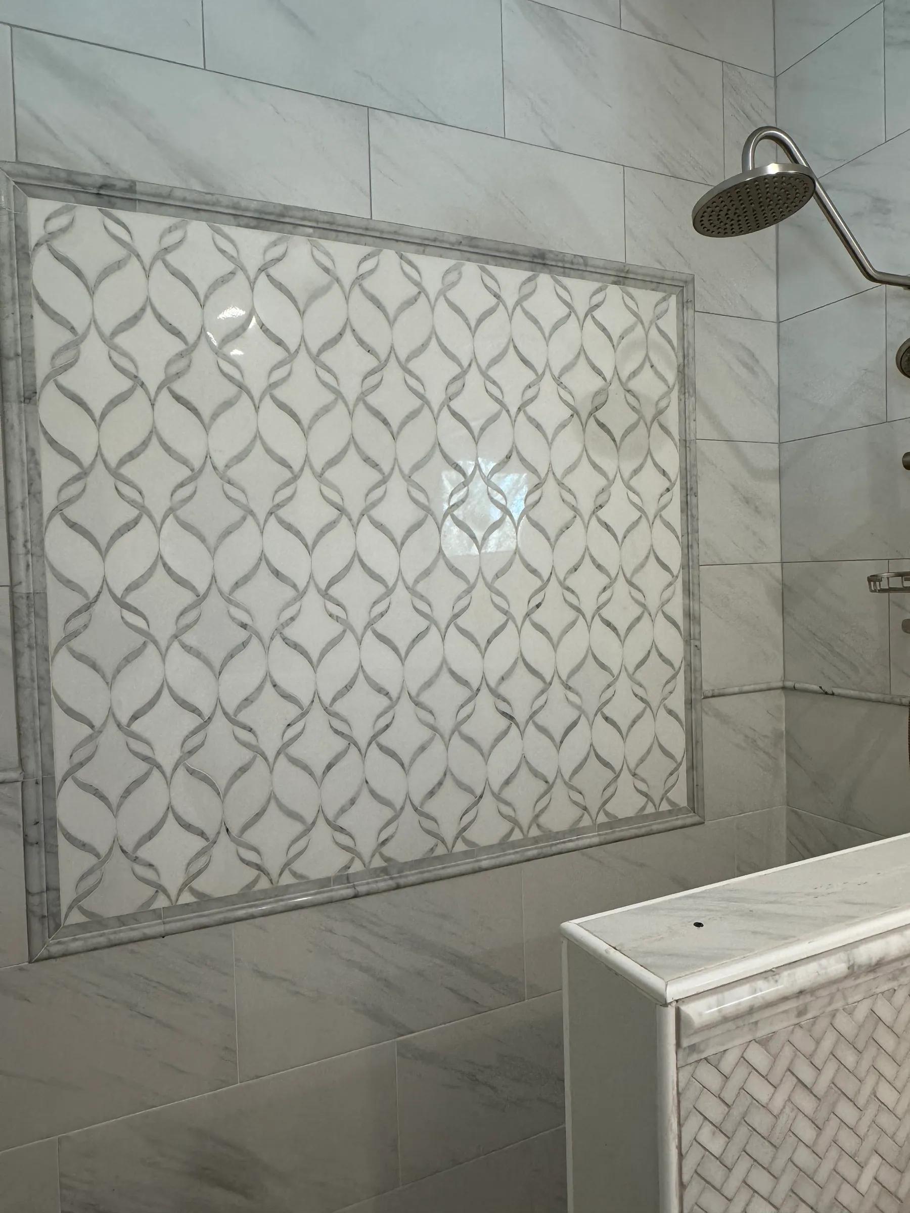 Walk-in shower with large marble-look tile and a framed decorative tile panel