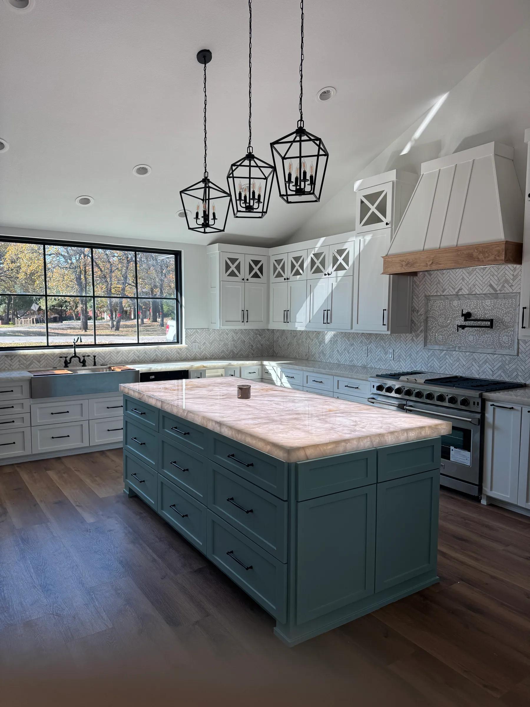 Remodeled kitchen with a long quartzite island, lantern pendants, and a professional range
