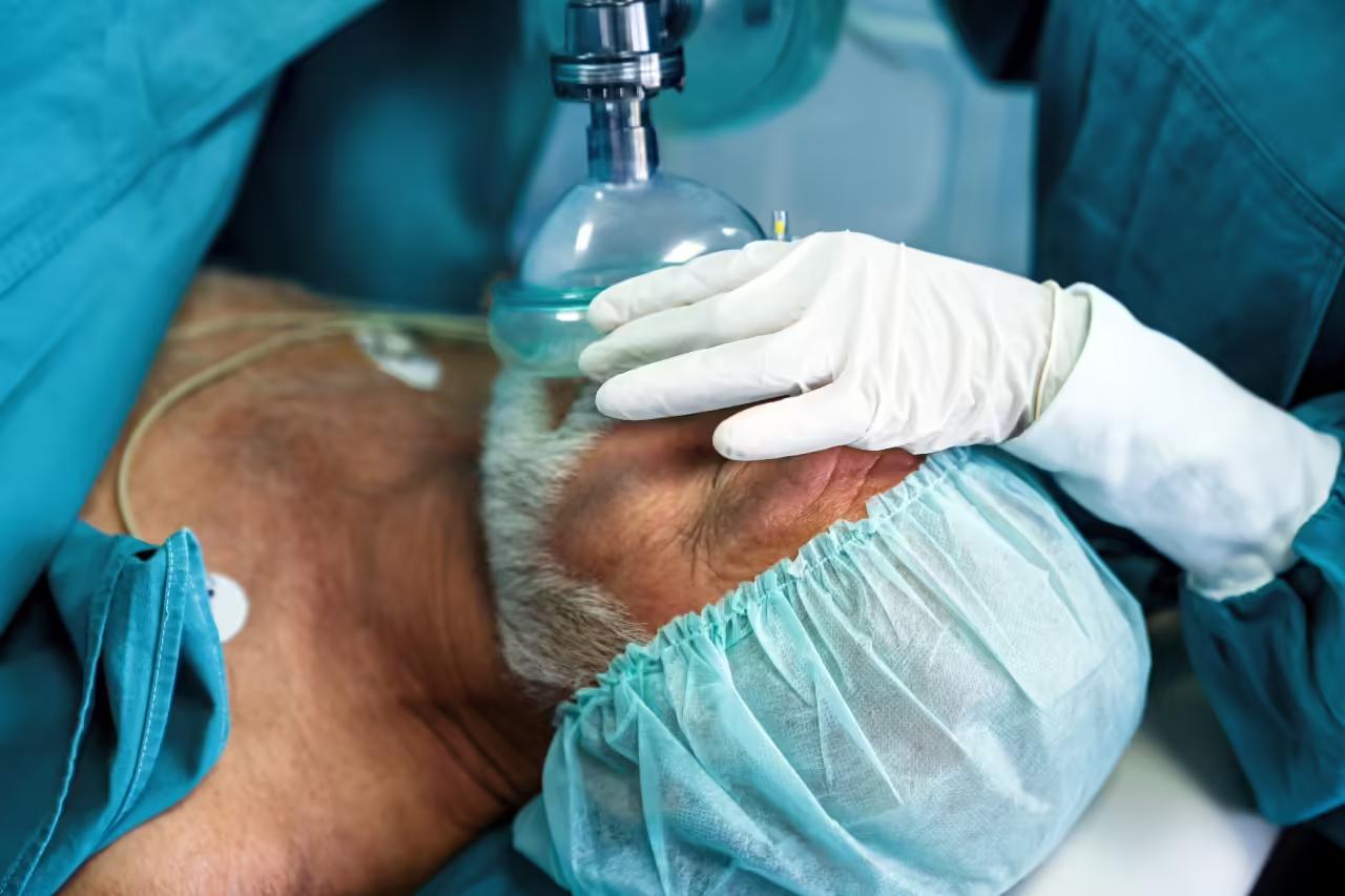 A surgical team operating under theatre lights, viewed past instruments on a sterile trolley