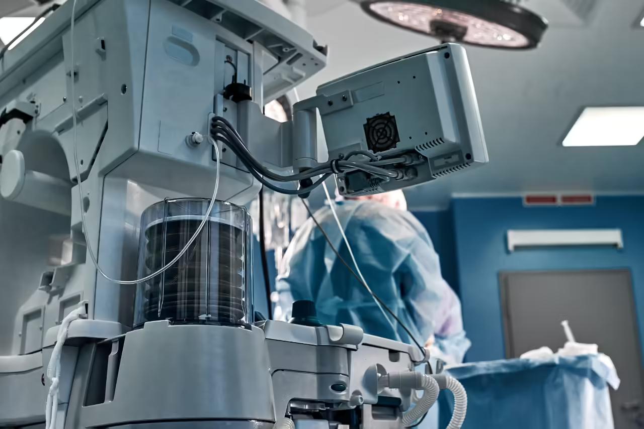 A robotic surgical system positioned beside an operating table, with a gowned theatre team working behind it