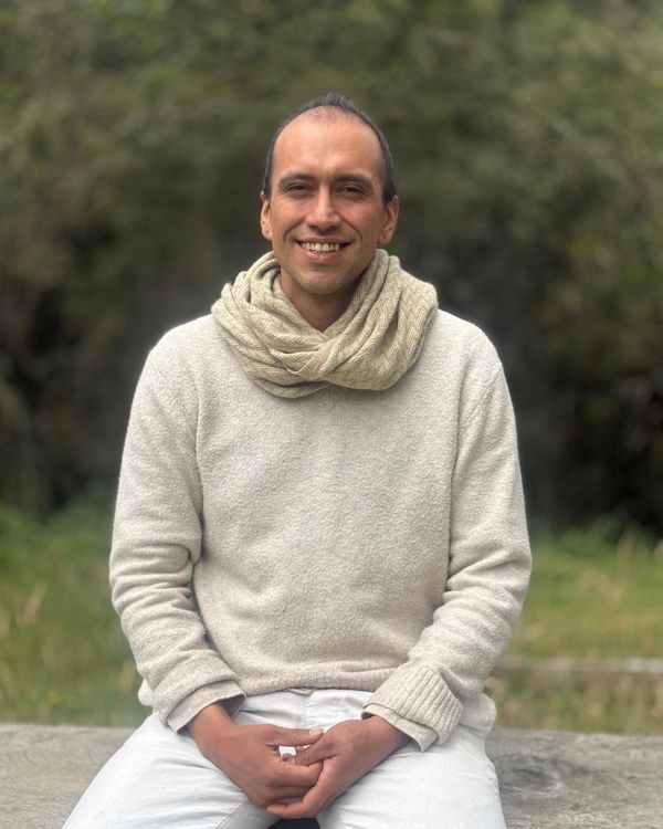 Diego Alejandro Torres Güiza sonriendo, sentado al aire libre con un saco claro y una bufanda