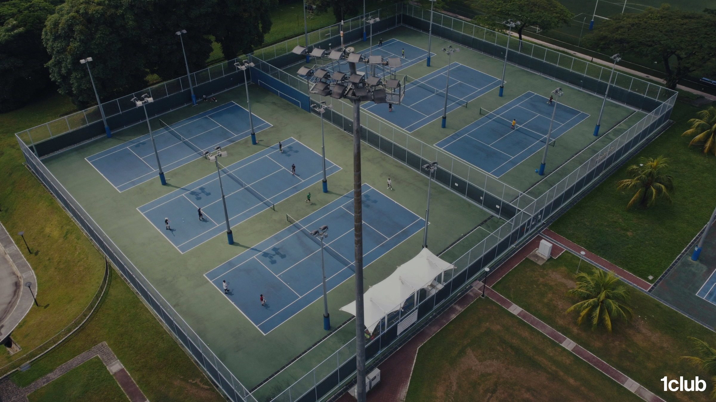 Drone view of a six-court tennis club with half the courts sitting empty