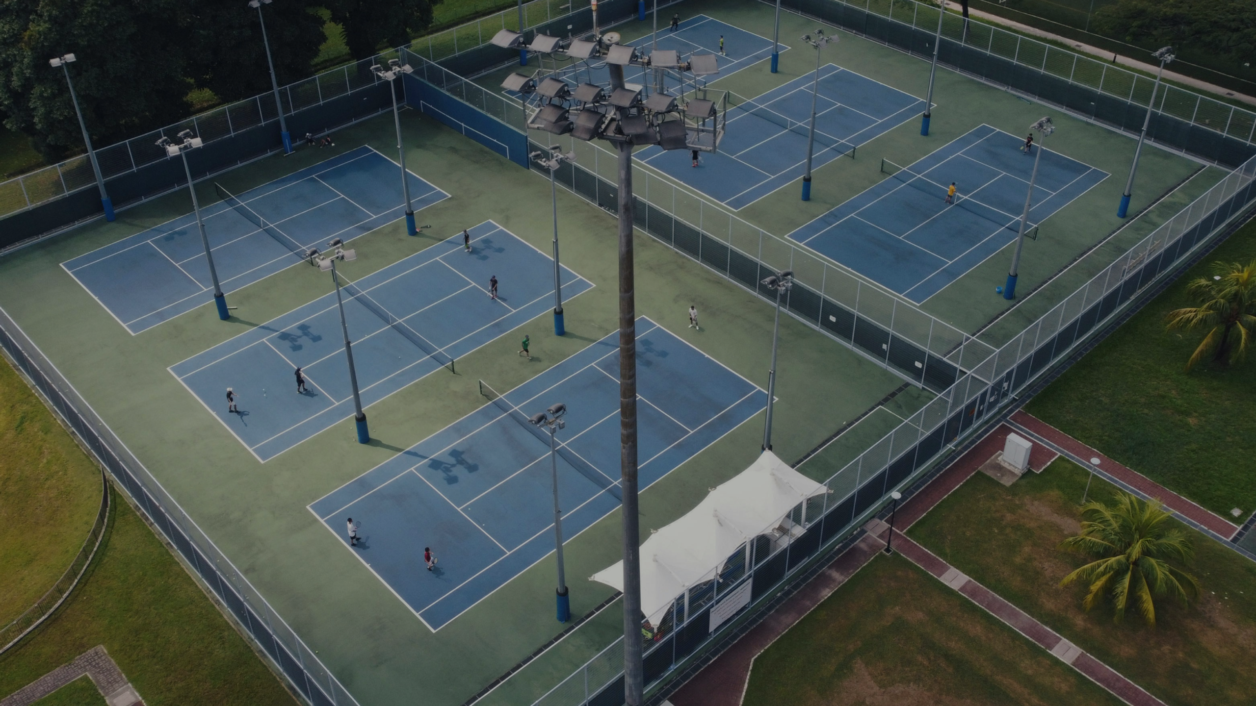 Drone view of a six-court tennis club with half the courts sitting empty