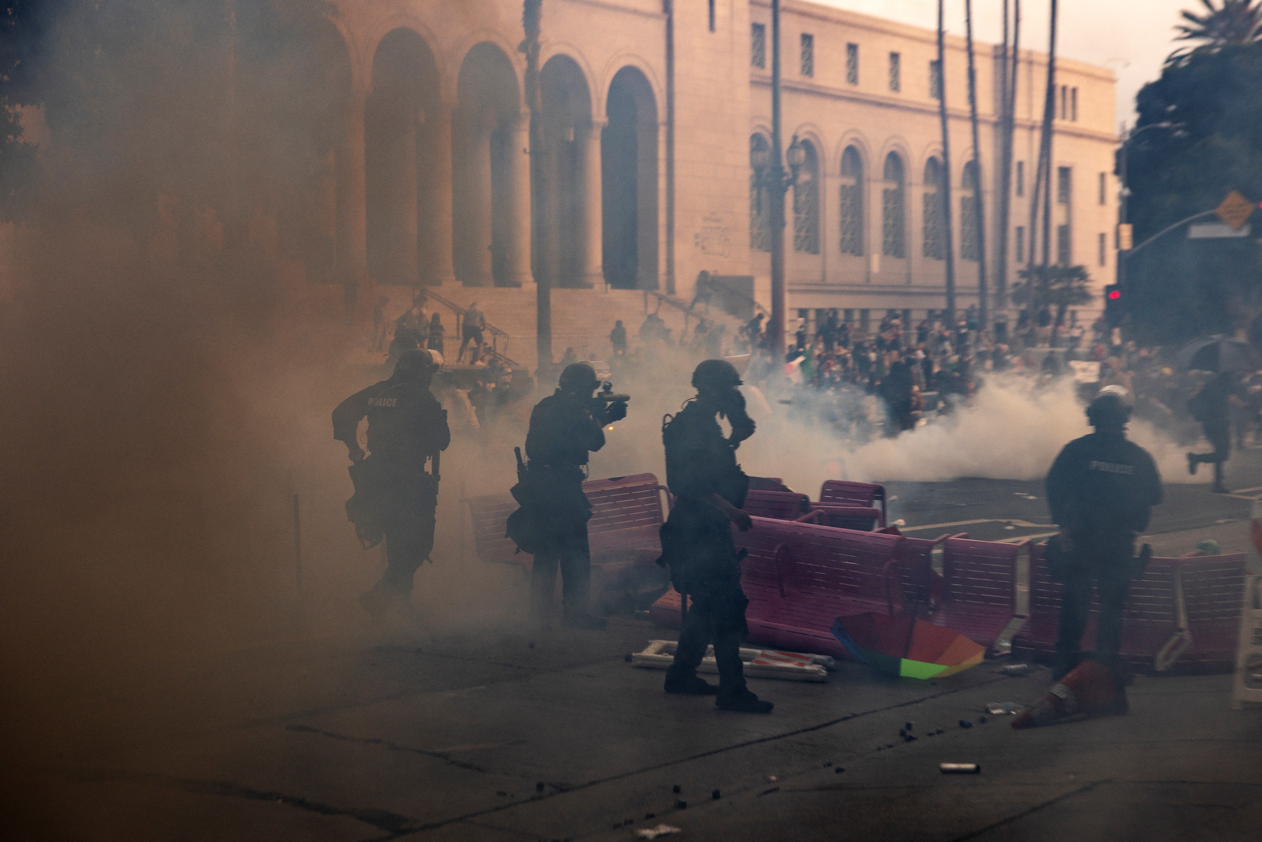 Members of the national guard with smoke around them, with protestors in the background.