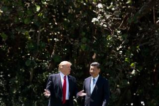 Two people, Donald Trump and Xi JinPing discuss while walking in a garden.