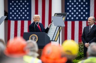 US President Donald Trump on stage holding a board with a list of countries and their allocation reciprocal tariffs, alongside Secretary of Commerce Howard Lutnick.