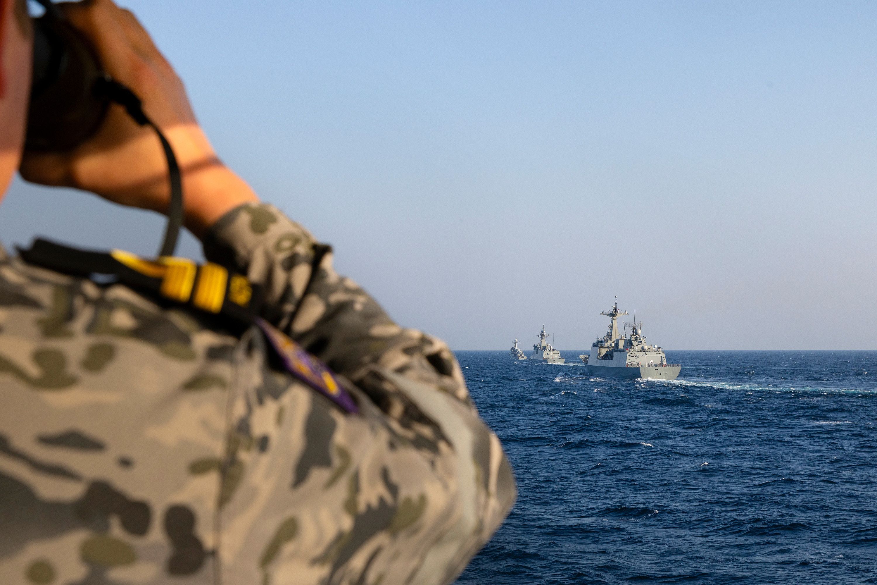 A Royal Australian Navy officer on HMAS Toowoomba observes three Republic of Korea Navy ships in formation during officer of the watch manoeuvres as part of a regional presence deployment in 2023.