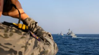 A Royal Australian Navy officer on HMAS Toowoomba observes three Republic of Korea Navy ships in formation during officer of the watch manoeuvres as part of a regional presence deployment in 2023.