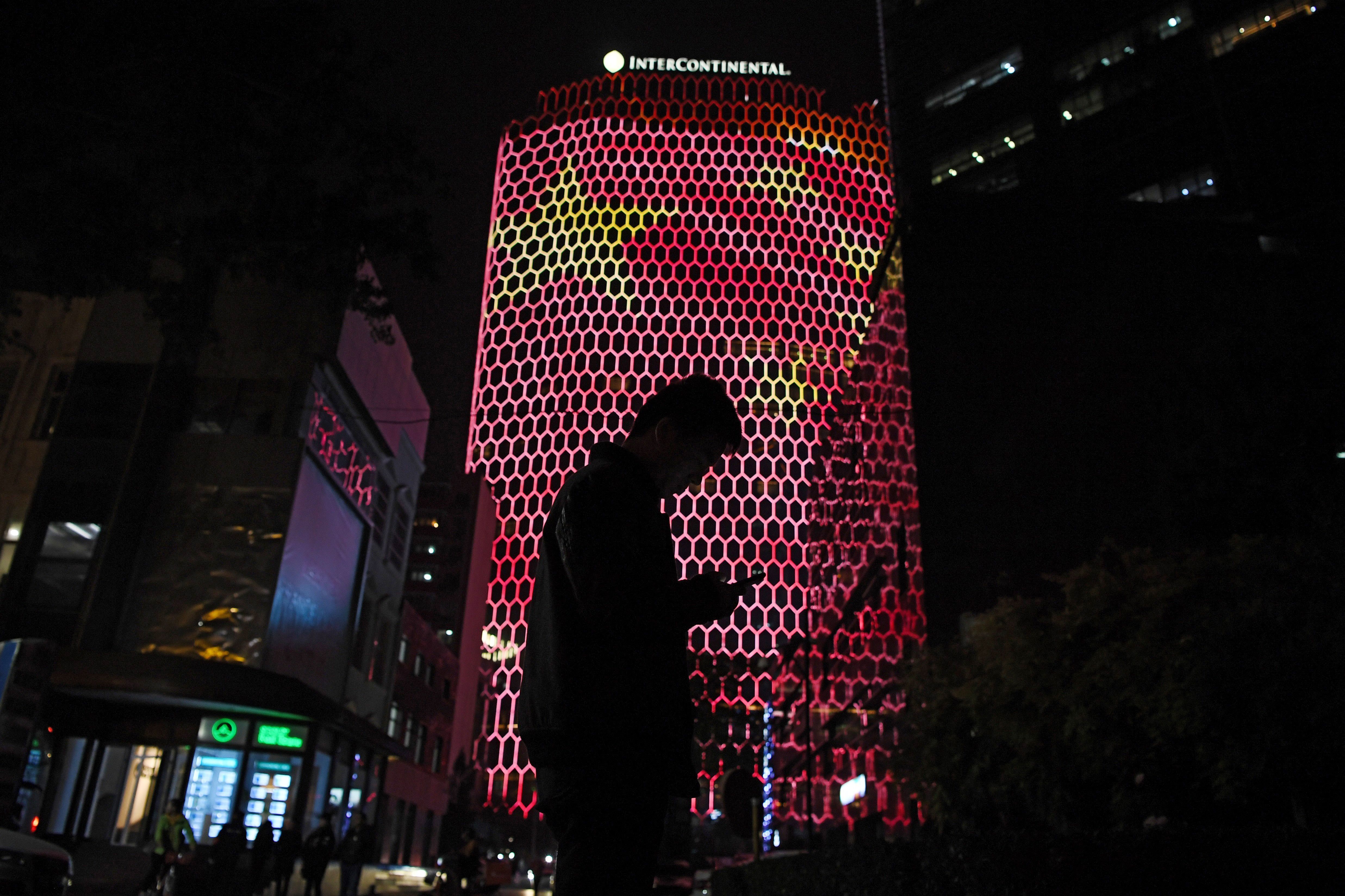A man looks at his phone near a giant image of the Chinese national flag on the side of a building in Beijing, during the ongoing 19th Communist Party Congress on October 23, 2017