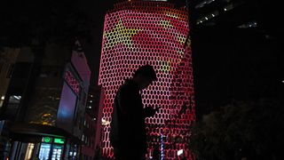A man looks at his phone near a giant image of the Chinese national flag on the side of a building in Beijing, during the ongoing 19th Communist Party Congress on October 23, 2017