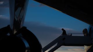 President Donald Trump disembarking from Air Force One at dusk.