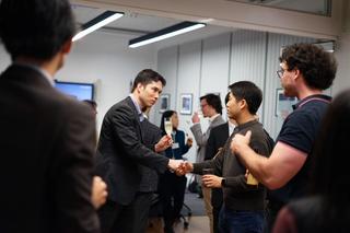 Two people shake hands at a networking event.