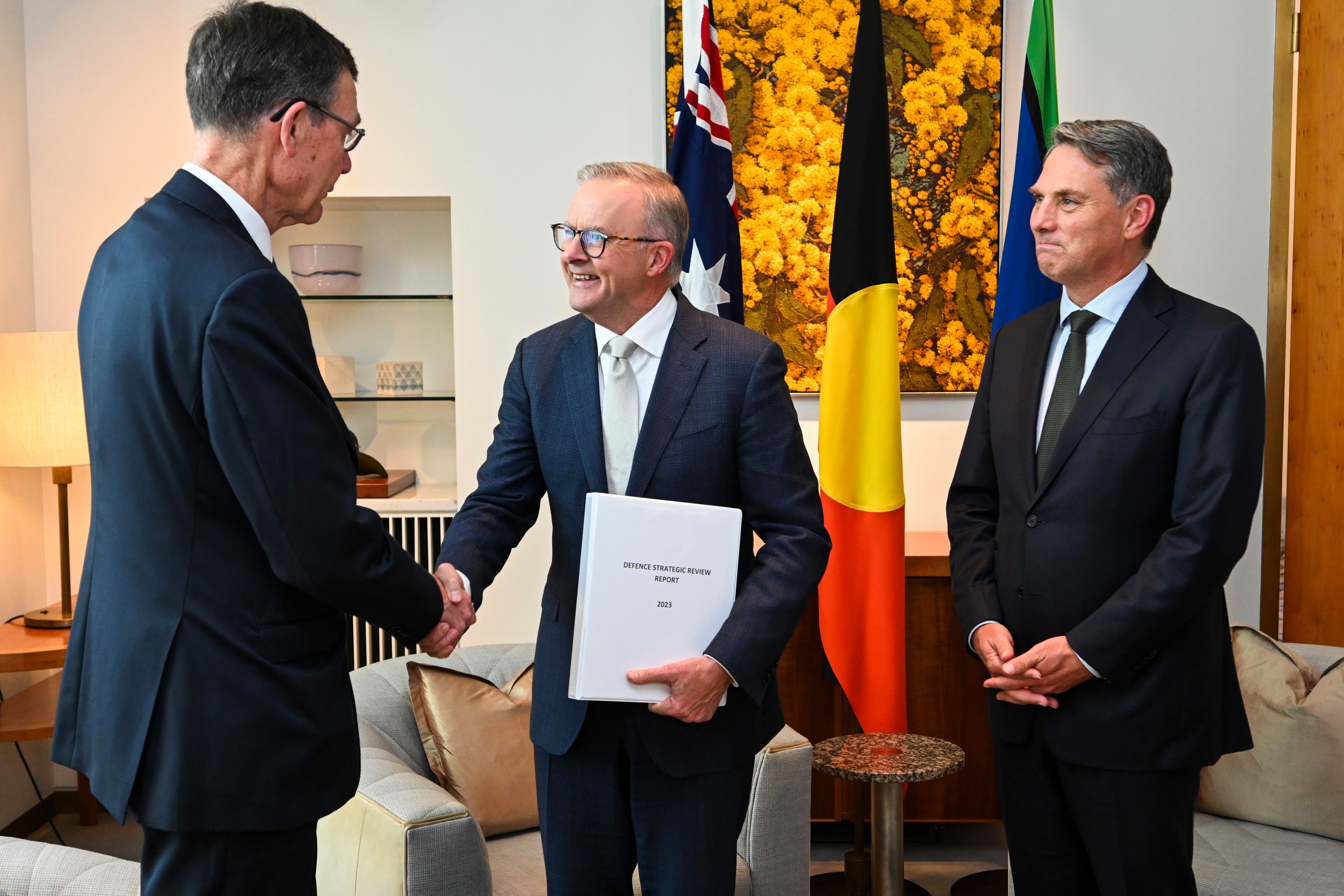 3 people meeting, with 2 shaking hands.