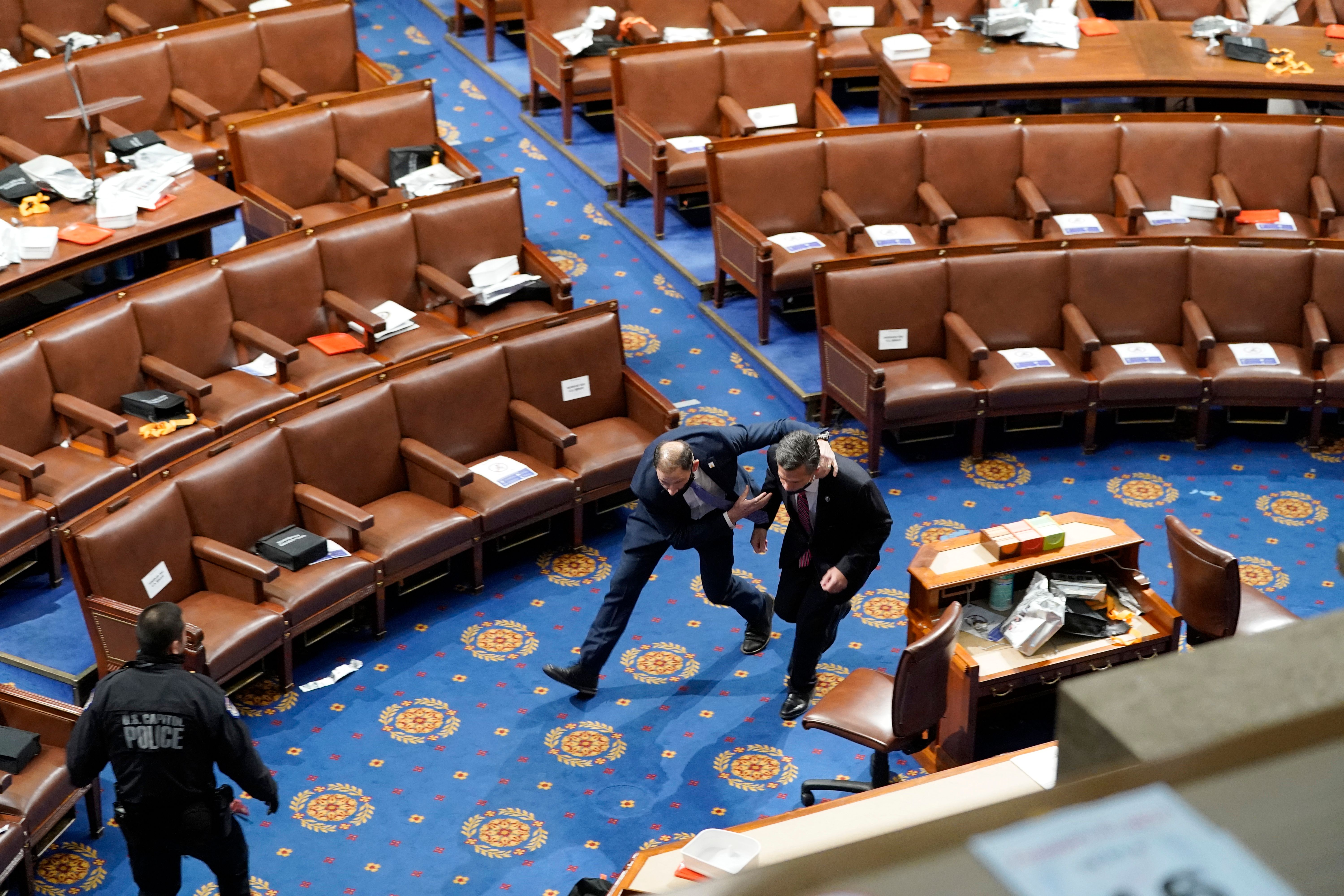 Members of congress run for cover as protesters try to enter the House Chamber during a joint session of Congress on January 06, 2021 in Washington, DC.