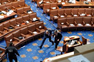 Members of congress run for cover as protesters try to enter the House Chamber during a joint session of Congress on January 06, 2021 in Washington, DC.